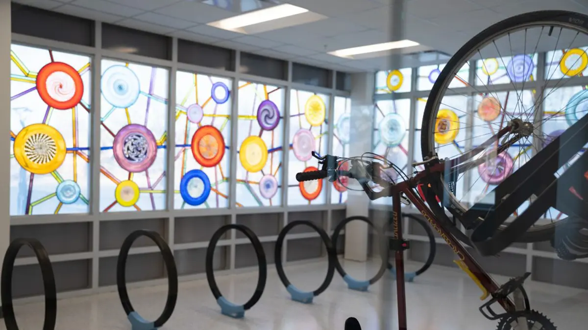 Bicycle handing from wall rack with a backdrop of colorful stained glass windows